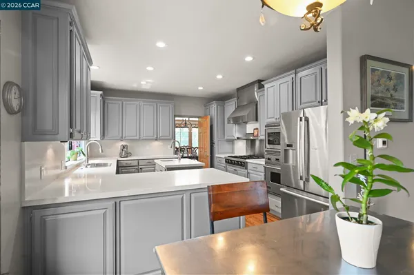 a kitchen with stainless steel appliances a dining table a sink a refrigerator and cabinets