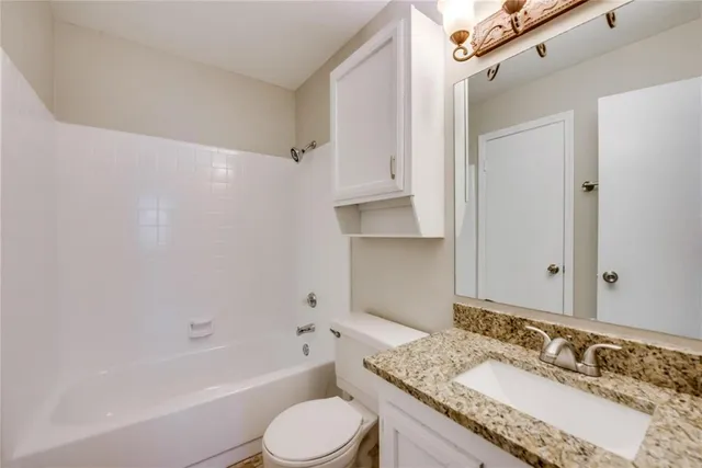 a bathroom with a granite countertop tub sink and mirror