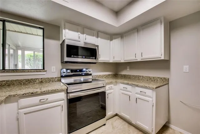 a kitchen with granite countertop a stove top oven microwave and cabinets