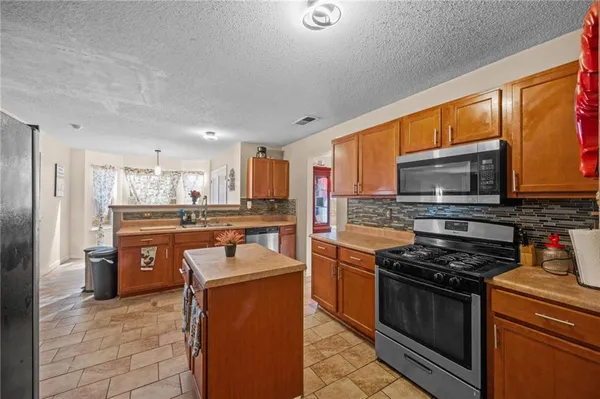 a kitchen with stainless steel appliances granite countertop a stove refrigerator sink and microwave