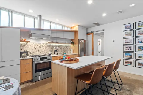 a kitchen with stainless steel appliances kitchen island granite countertop a table chairs stove and refrigerator