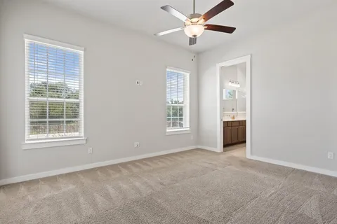 an empty room with chandelier fan and windows