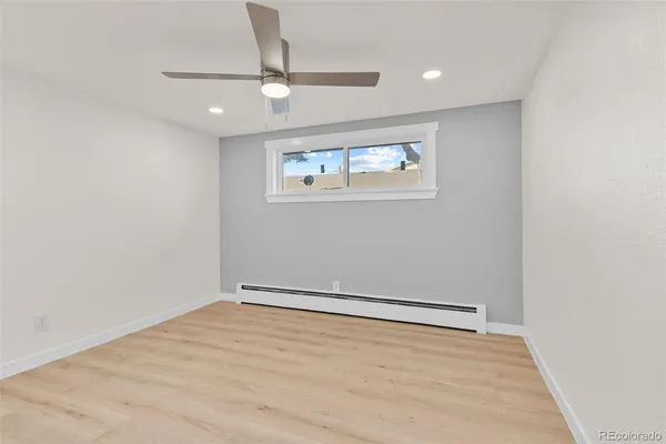 an empty room with wooden floor and ceiling fan