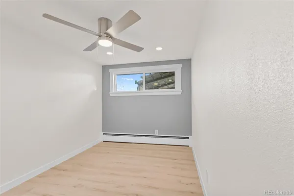 an empty room with wooden floor and ceiling fan