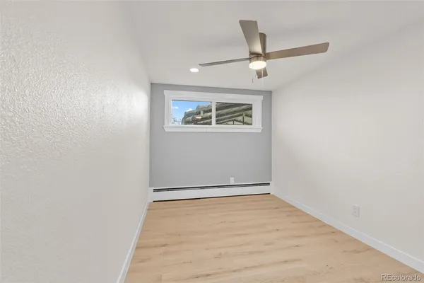 an empty room with wooden floor ceiling fan and windows