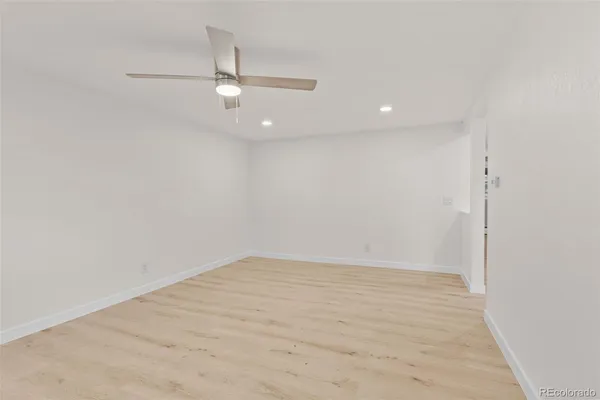 an empty room with wooden floor ceiling fan and window
