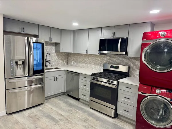 a kitchen with cabinets stainless steel appliances and wooden floor