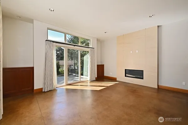 a view of an empty room with wooden floor and a fireplace