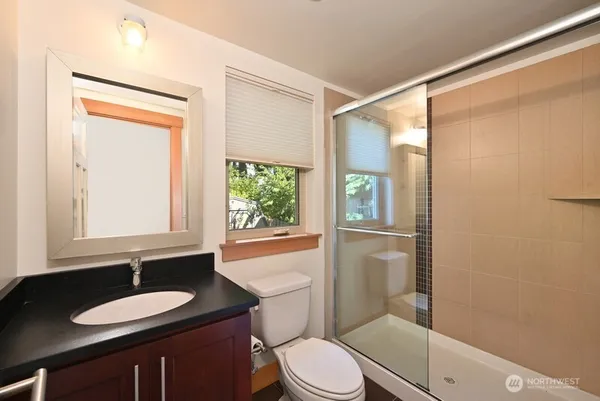 a bathroom with a granite countertop sink toilet a mirror and shower