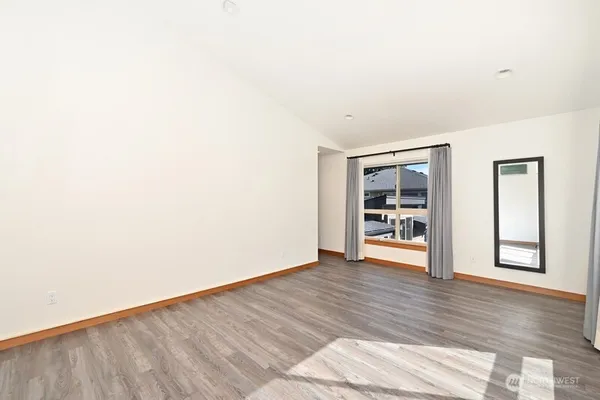 a view of an empty room with window and wooden floor