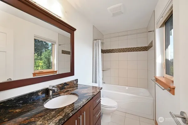 a bathroom with a granite countertop sink toilet a mirror and bathtub