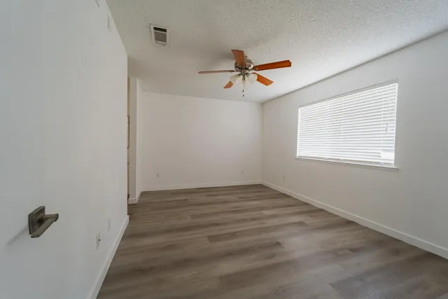 a view of empty room with wooden floor and fan