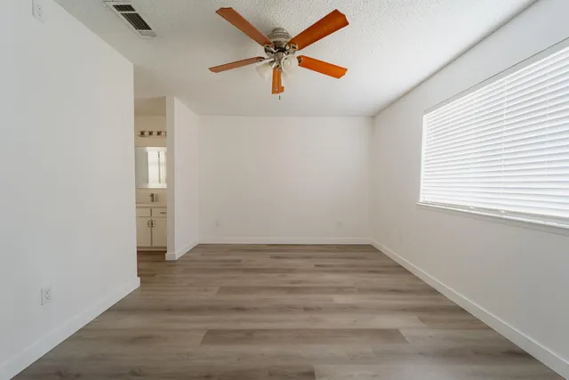 an empty room with wooden floor and windows