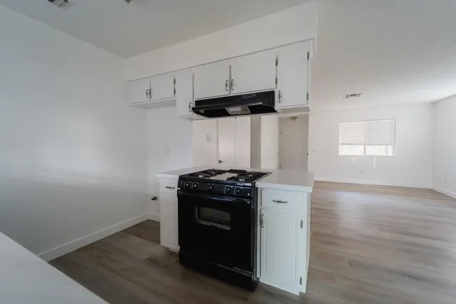 a kitchen with a stove and a wooden floor
