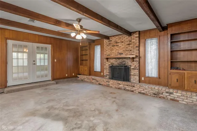 an empty room with fireplace cabinet and windows