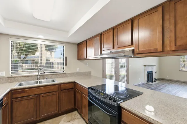 a kitchen with granite countertop stainless steel appliances a sink stove and cabinets