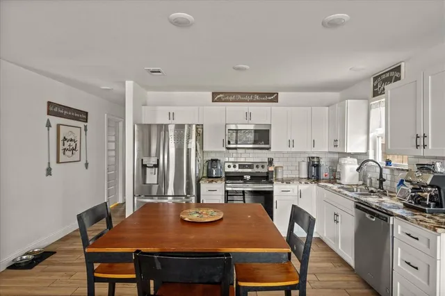 a kitchen with stainless steel appliances granite countertop a stove a refrigerator a kitchen island a table and chairs