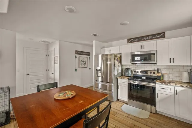 a kitchen with stainless steel appliances granite countertop a stove a refrigerator a oven a sink with a dining table and chairs