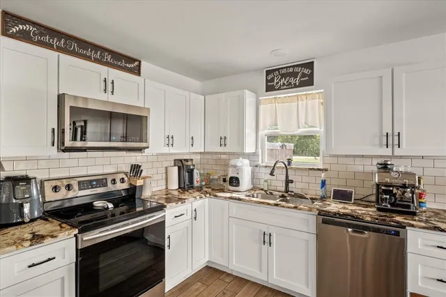 a kitchen with granite countertop a stove sink and cabinets