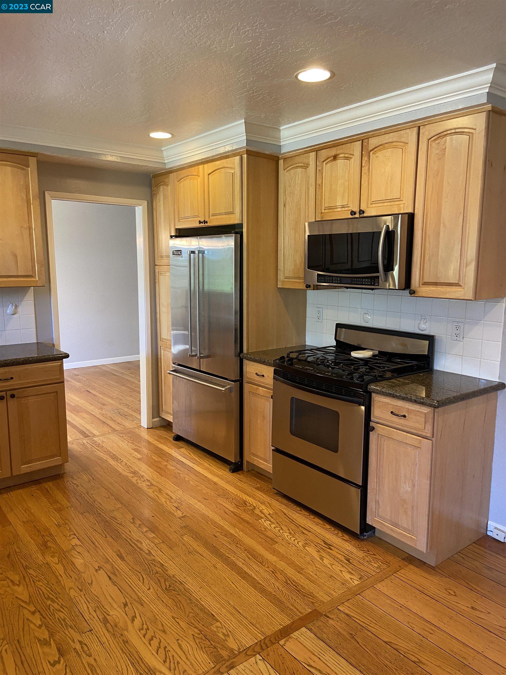 2202 Cascade Drive Walnut Creek, CA 94598 - Photo 7 of 23 a kitchen with granite countertop a refrigerator and a stove top oven