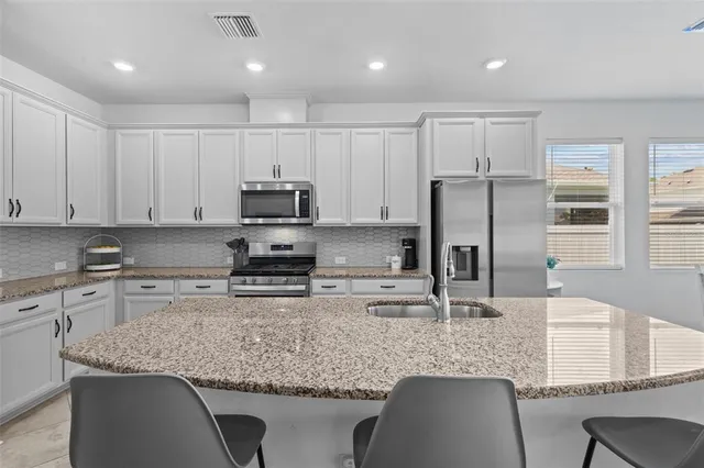 a kitchen with stainless steel appliances granite countertop a sink refrigerator and microwave