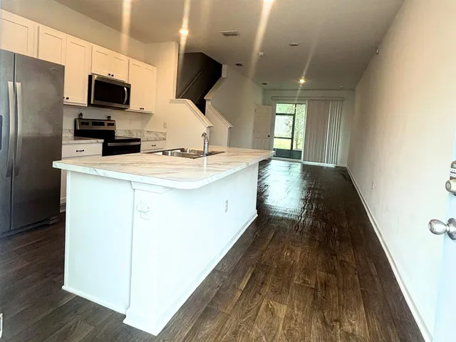 a kitchen with kitchen island wooden floors appliances and sink