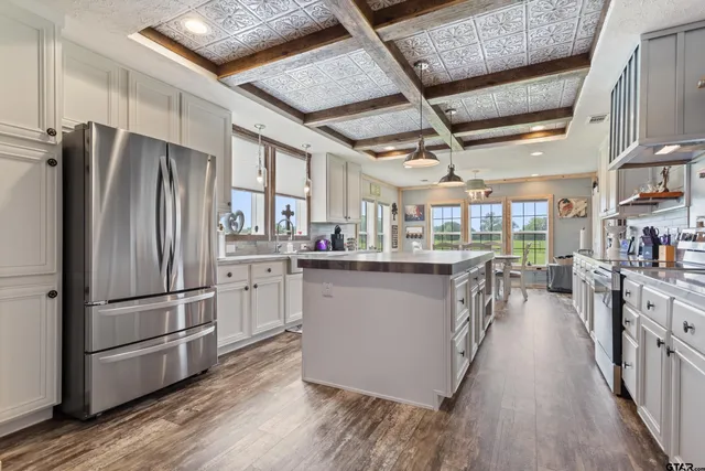 a kitchen with stainless steel appliances granite countertop a refrigerator a stove and a wooden floors