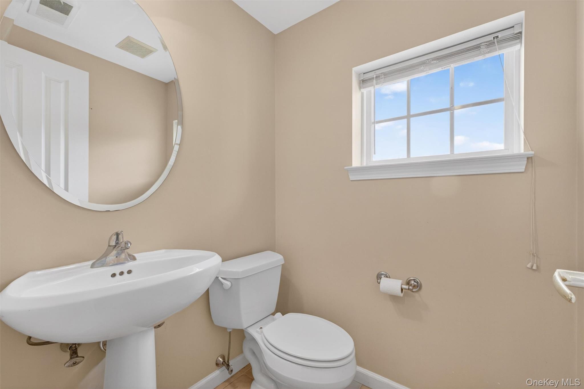 422 Highridge Court, Unit 422 Peekskill, NY 10566 - Photo 16 of 45 Conveniently located just off the kitchen at the base of the staircase leading to the second level, the spacious half bath offers both function and style. This well-appointed powder room features a classic pedestal sink, a decorative mirror, and a toilet, providing an ideal and easily accessible space for guests while complementing the home’s thoughtful layout.