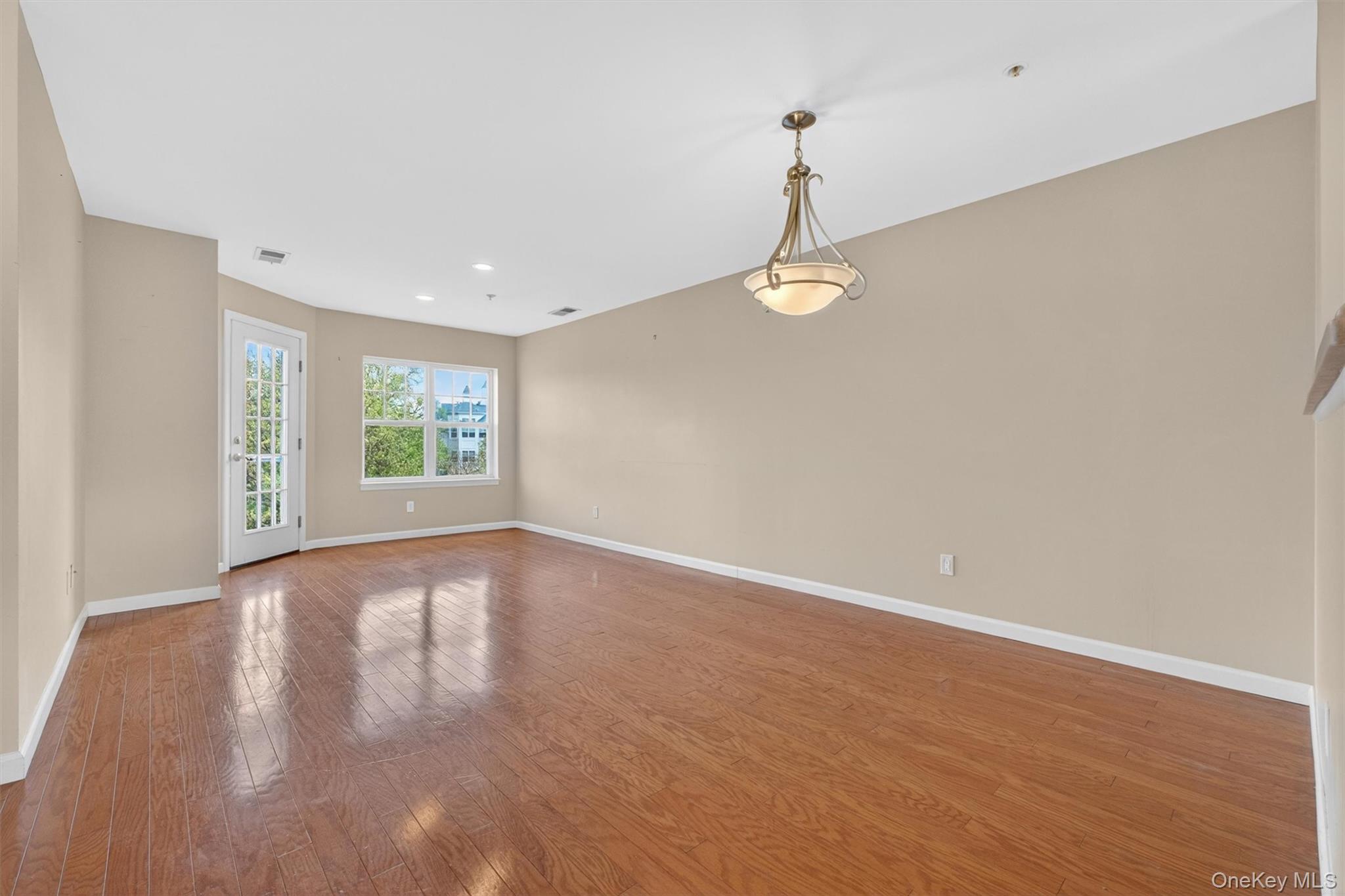 422 Highridge Court, Unit 422 Peekskill, NY 10566 - Photo 6 of 45 The spacious family room is a standout feature, offering a bright and inviting atmosphere enhanced by a dramatic wall of windows that capture beautiful seasonal river views. Filled with natural light throughout the day, this welcoming space is complemented by gleaming hardwood floors, creating the perfect setting for both relaxed everyday living and effortless entertaining.