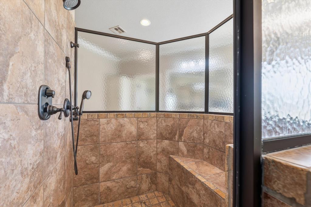 504 Casa Del Rancho Road Lorena, TX 76655 - Photo 24 of 40 Walk-in shower featuring bronze fixtures, a built-in bench, textured privacy glass, ceiling-mounted shower head, and a handheld shower attachment