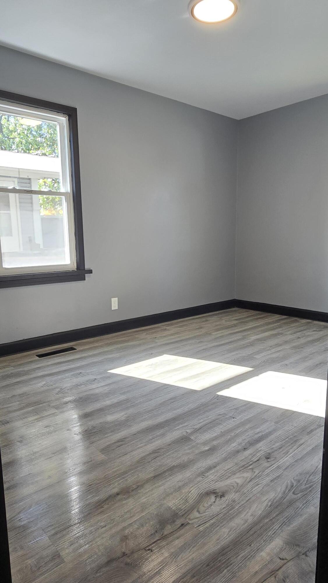 2854 Hancock Street Gary, IN 46405 - Photo 3 of 13 a view of an empty room with wooden floor and a window