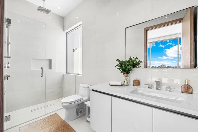 a bathroom with a granite countertop sink a toilet a mirror and shower