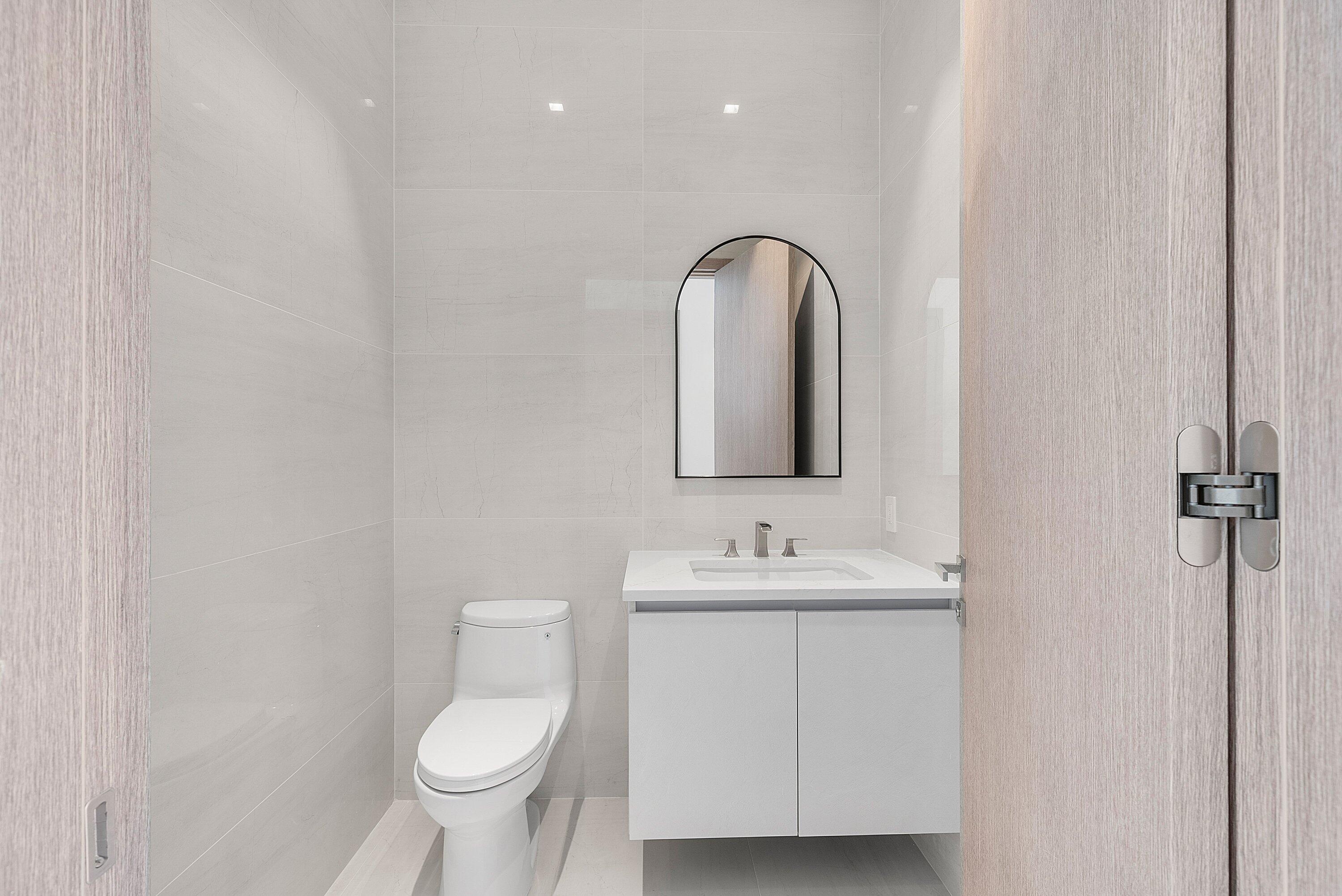 246 Northeast 6th Avenue, Unit PH Delray Beach, FL 33483 - Photo 29 of 36 a bathroom with a toilet sink and mirror