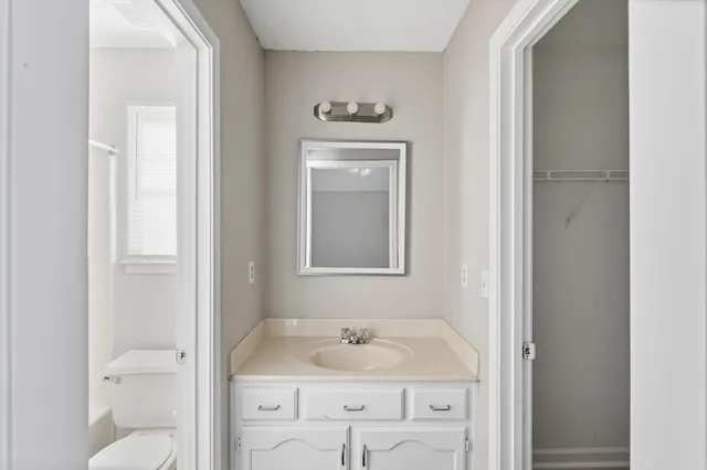 a bathroom with a granite countertop sink toilet and mirror