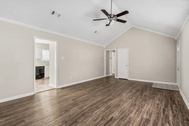 an empty room with wooden floor ceiling fan and windows