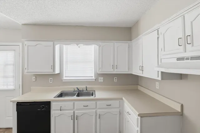 a kitchen with white cabinets sink and window