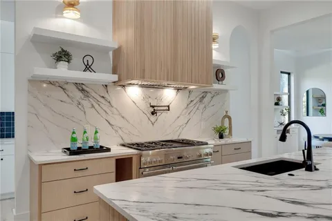 a kitchen with stainless steel appliances granite countertop a sink a stove and wooden cabinets