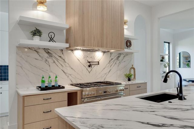 a kitchen with stainless steel appliances granite countertop a sink a stove and wooden cabinets