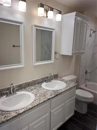 a bathroom with a granite countertop toilet sink and mirror