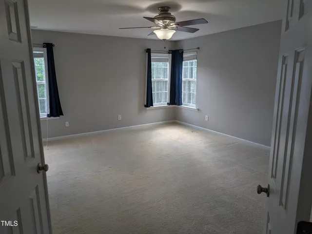 an empty room with windows and fan