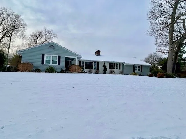 a front view of house with yard and trees in the background