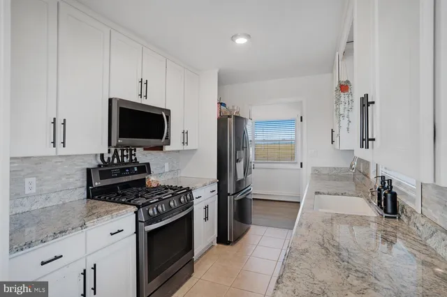 a kitchen with granite countertop a sink stove and cabinets