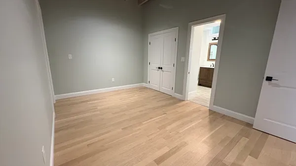 an empty room with wooden floor and entrance