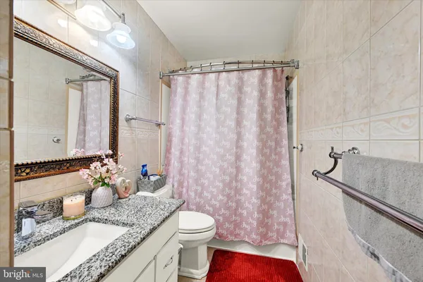 a bathroom with a granite countertop sink mirror vanity and toilet
