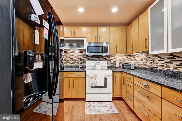 a kitchen with stainless steel appliances kitchen island granite countertop a refrigerator and cabinets
