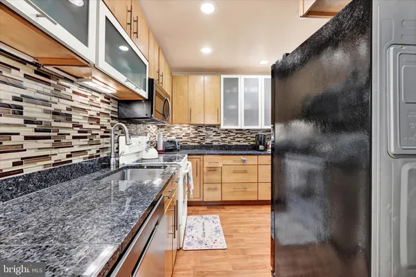 a kitchen with stainless steel appliances granite countertop a stove a sink and a refrigerator