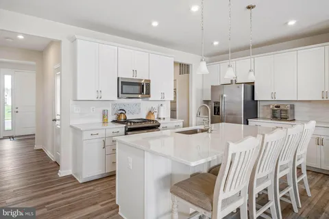 a kitchen with stainless steel appliances granite countertop a refrigerator a stove microwave and white cabinets with wooden floor