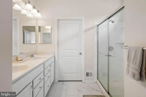 a bathroom with a double vanity sink a mirror and a shower