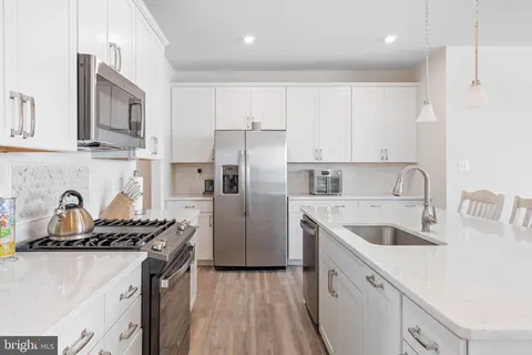 a kitchen with stainless steel appliances granite countertop a sink stove refrigerator and cabinets