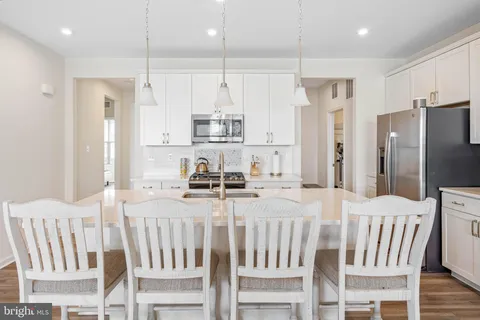 a kitchen with stainless steel appliances kitchen island granite countertop a table chairs refrigerator and microwave